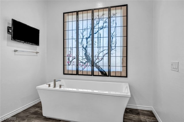 bathroom featuring a freestanding tub, wood finished floors, and baseboards