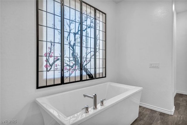 full bathroom featuring a soaking tub, baseboards, and wood finished floors