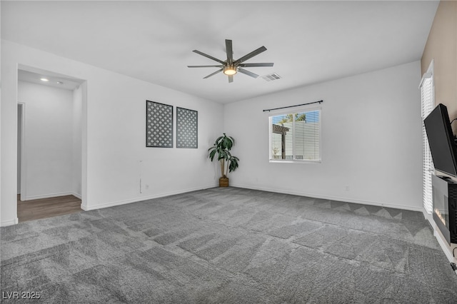 carpeted spare room with baseboards, visible vents, and ceiling fan