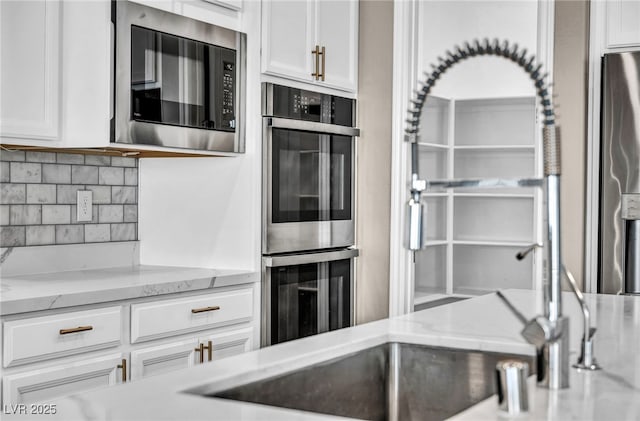 kitchen with wine cooler, backsplash, appliances with stainless steel finishes, and white cabinetry