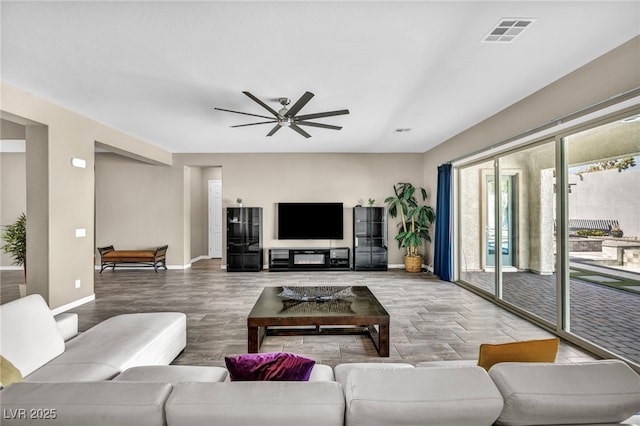 living room featuring wood finished floors, baseboards, visible vents, and ceiling fan