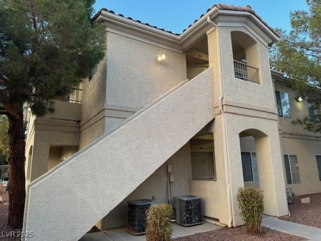 back of property with central AC unit and stucco siding