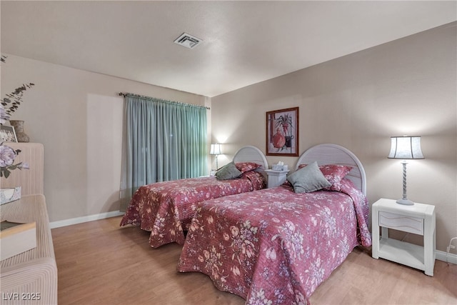 bedroom featuring wood finished floors, visible vents, and baseboards