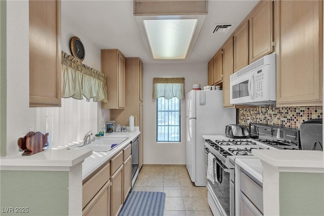 kitchen with white microwave, range with gas cooktop, dishwasher, decorative backsplash, and a sink