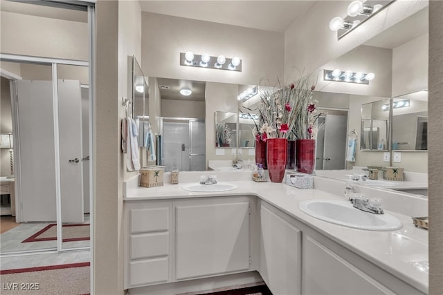 full bath with a shower stall, double vanity, and a sink