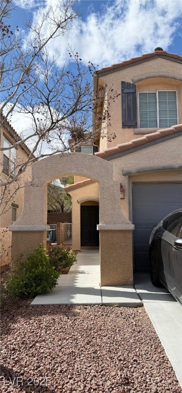 view of front of house featuring an attached garage, fence, stucco siding, driveway, and a gate