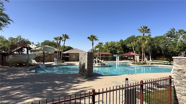 pool featuring a patio, a water slide, and fence