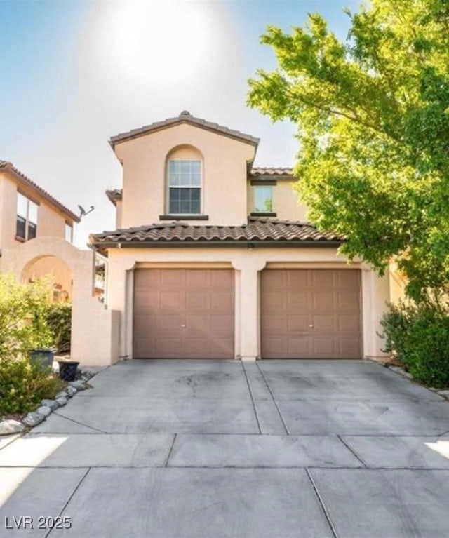 mediterranean / spanish-style house featuring stucco siding, concrete driveway, an attached garage, and a tiled roof