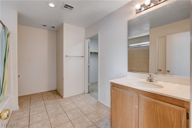 full bathroom with a walk in closet, tile patterned floors, visible vents, and vanity