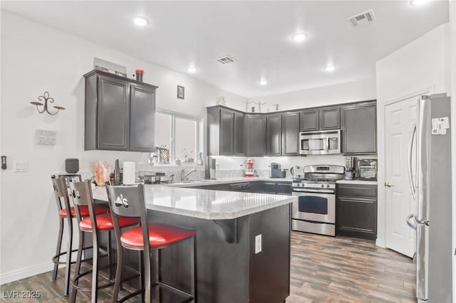 kitchen featuring a breakfast bar, a peninsula, visible vents, and stainless steel appliances