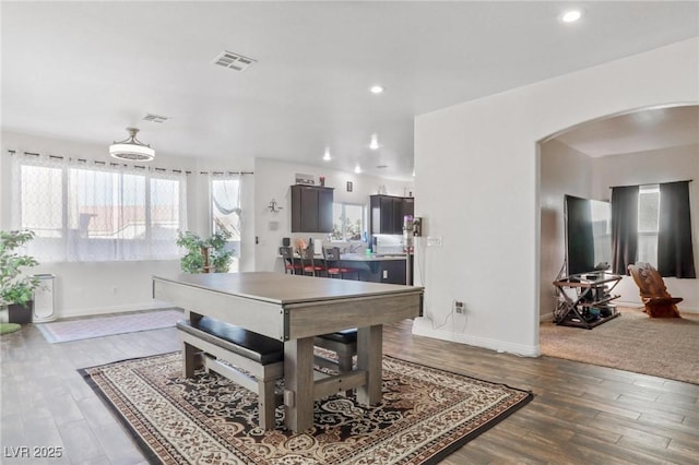 dining room featuring visible vents, wood finished floors, arched walkways, and baseboards