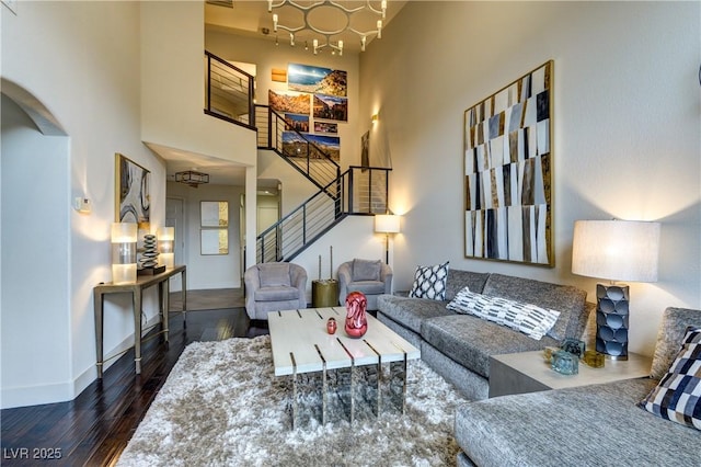 living room with hardwood / wood-style floors, baseboards, a towering ceiling, and stairs