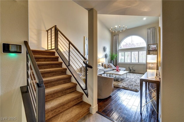 stairway featuring a high ceiling, an inviting chandelier, and wood finished floors