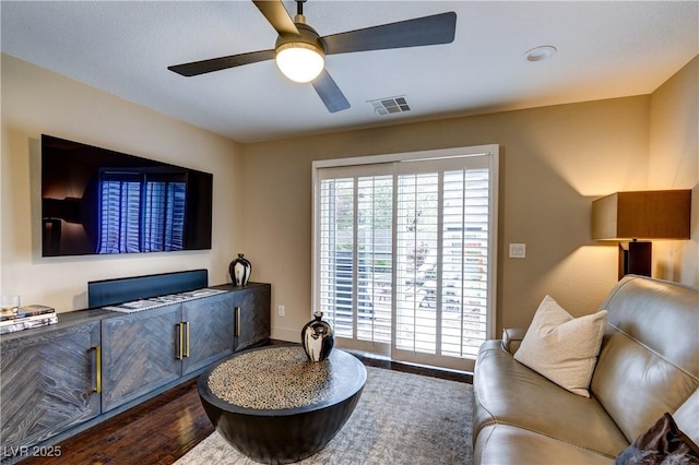 living area with visible vents, dark wood-type flooring, and a ceiling fan