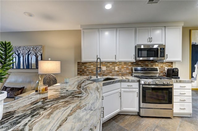 kitchen featuring decorative backsplash, white cabinetry, appliances with stainless steel finishes, and a sink