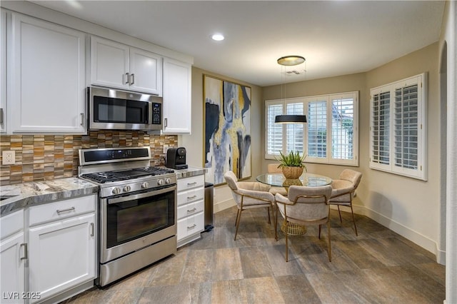 kitchen with stainless steel appliances, baseboards, tasteful backsplash, and white cabinetry