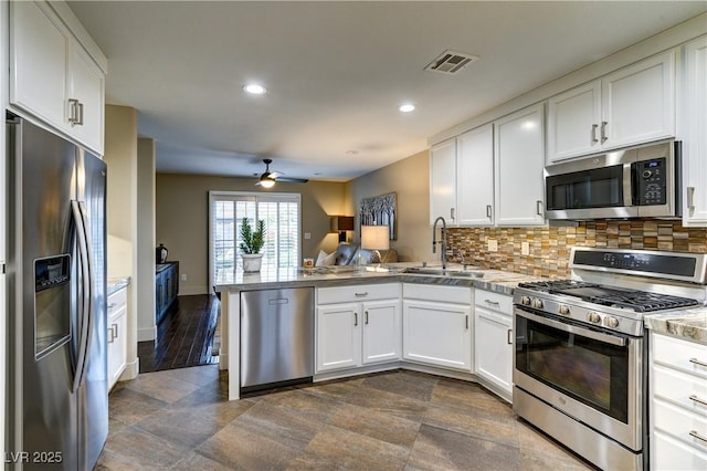 kitchen with visible vents, decorative backsplash, a peninsula, stainless steel appliances, and white cabinetry