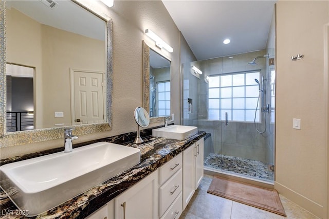 bathroom with double vanity, a shower stall, and a sink