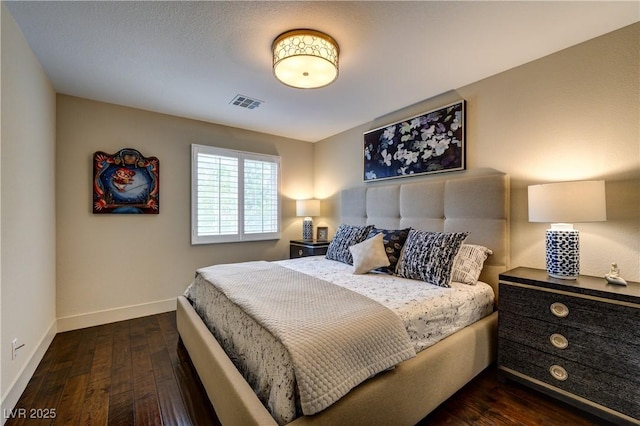 bedroom with dark wood-style floors, visible vents, and baseboards