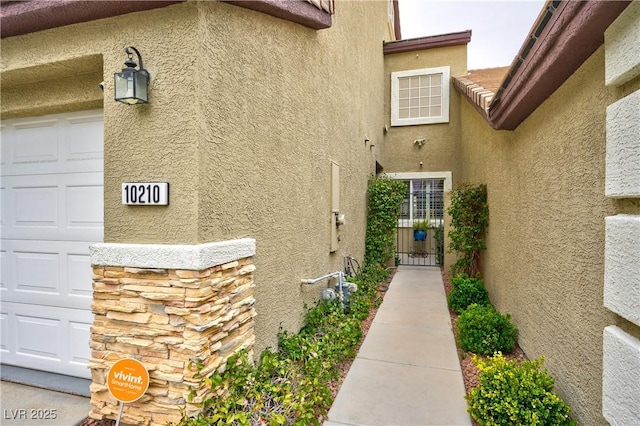 view of property exterior with stucco siding, an attached garage, and a gate