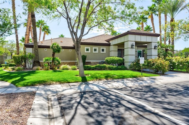 view of front of property featuring stucco siding, a tiled roof, and a front lawn