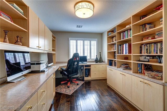 home office featuring visible vents, a textured ceiling, dark wood-style flooring, and built in study area