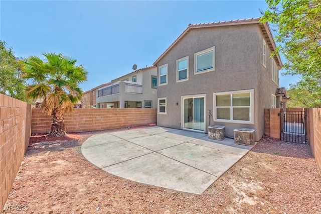 rear view of property with a patio area, stucco siding, a fenced backyard, and a gate