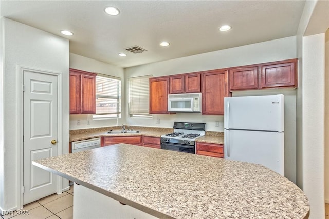 kitchen featuring white appliances, light tile patterned floors, visible vents, a sink, and light countertops