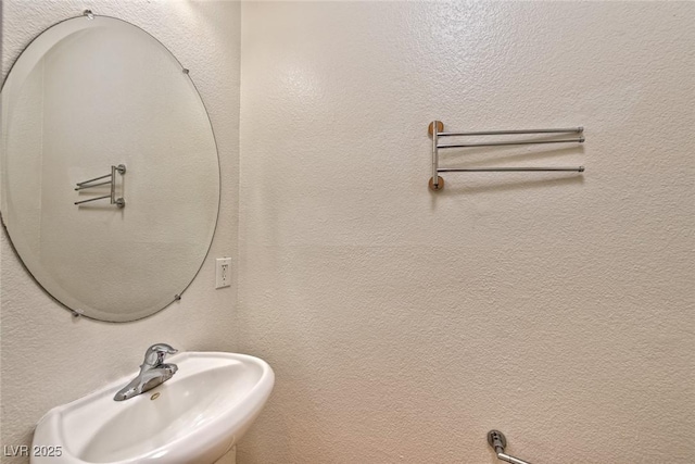 bathroom featuring a sink and a textured wall