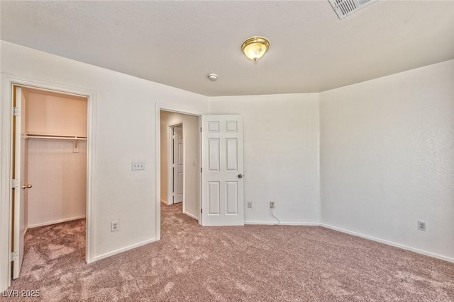 unfurnished bedroom featuring a spacious closet, visible vents, baseboards, carpet flooring, and a closet