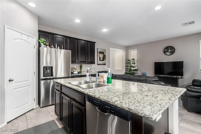 kitchen with visible vents, a sink, open floor plan, appliances with stainless steel finishes, and a kitchen island with sink