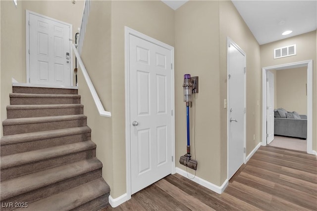 staircase featuring visible vents, baseboards, and wood finished floors