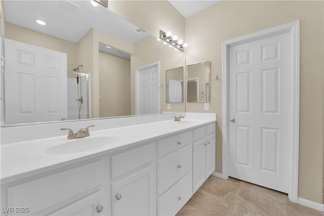 full bathroom featuring double vanity, walk in shower, baseboards, and a sink