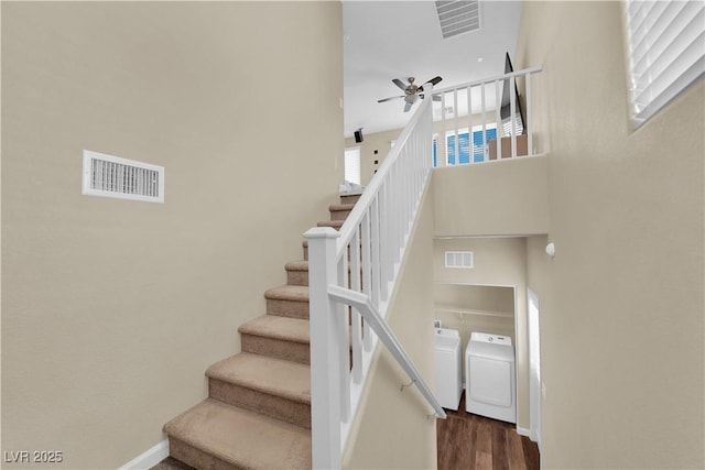 stairs with visible vents, separate washer and dryer, and a ceiling fan