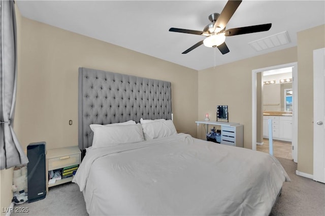 bedroom with baseboards, visible vents, ensuite bath, ceiling fan, and light colored carpet