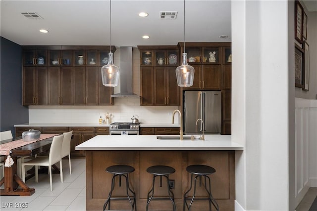 kitchen featuring visible vents, tasteful backsplash, appliances with stainless steel finishes, and wall chimney range hood