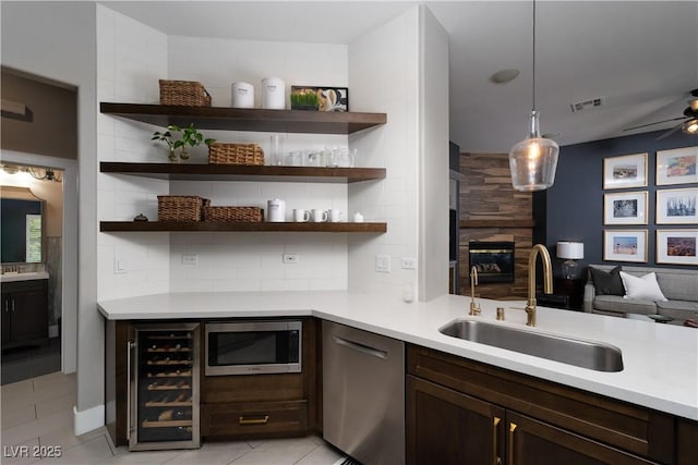 kitchen with a sink, wine cooler, dark brown cabinetry, appliances with stainless steel finishes, and decorative backsplash