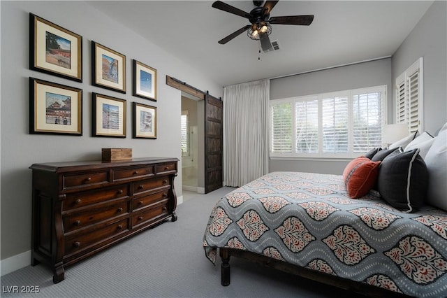 bedroom with visible vents, baseboards, a barn door, carpet floors, and a ceiling fan