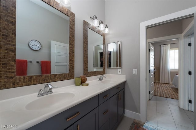 ensuite bathroom featuring tile patterned flooring, connected bathroom, double vanity, and a sink