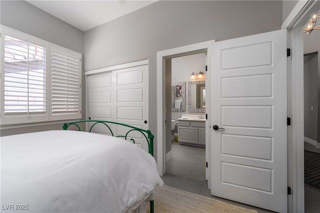 bedroom with a closet, light tile patterned flooring, and ensuite bathroom