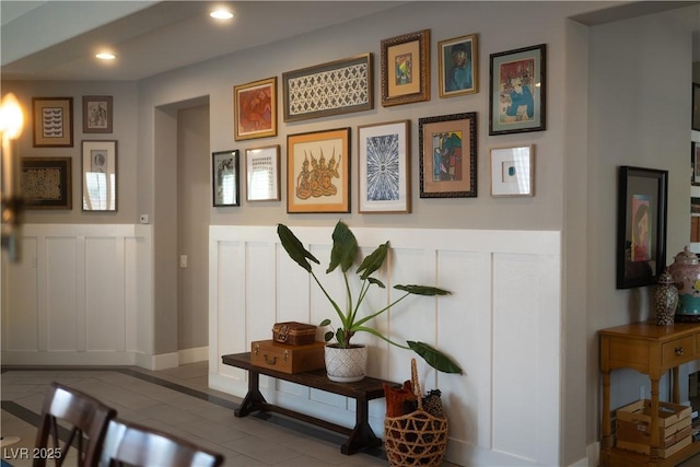 interior space featuring recessed lighting, a wainscoted wall, tile patterned flooring, and a decorative wall