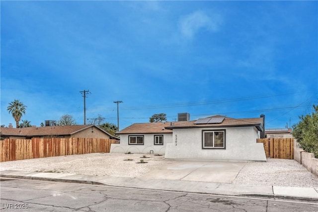 rear view of house with a patio area, stucco siding, solar panels, and a fenced backyard