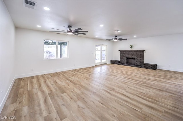 unfurnished living room with visible vents, a healthy amount of sunlight, a fireplace, and light wood-type flooring