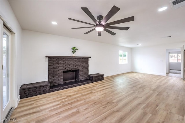 unfurnished living room featuring visible vents, a fireplace, baseboards, and wood finished floors