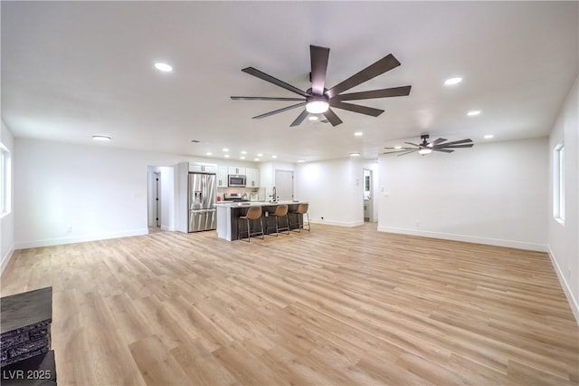 unfurnished living room with recessed lighting, light wood-style floors, and baseboards