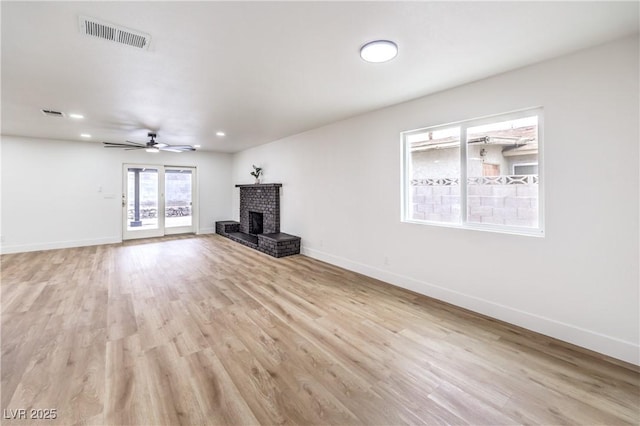 unfurnished living room with visible vents, baseboards, light wood-style flooring, a fireplace, and a ceiling fan