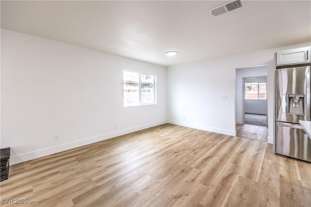 unfurnished room with light wood finished floors, visible vents, and baseboards