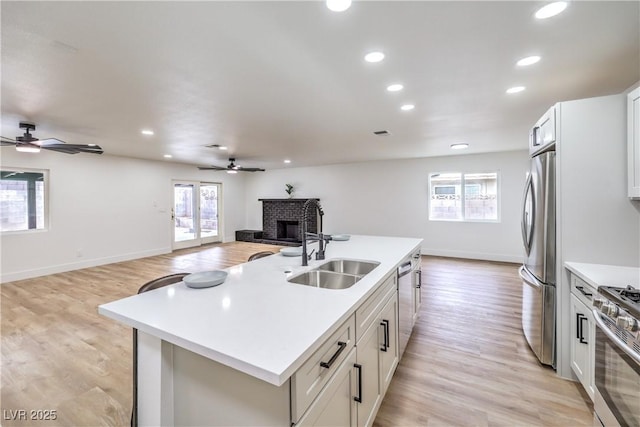 kitchen with open floor plan, light countertops, light wood-style floors, stainless steel appliances, and a sink