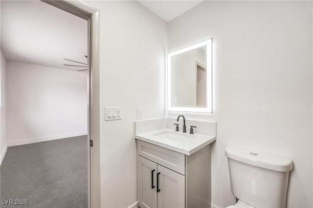 half bath with toilet, vanity, and baseboards