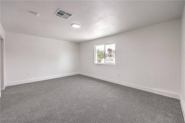 unfurnished room with baseboards, visible vents, and dark carpet